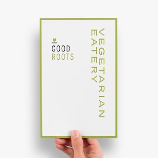 A hand holding a menu insert printed with Good Roots Vegetarian Eatery in black and light green.