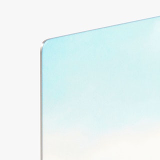 The rounded corner of a metal print with a light blue and white background.