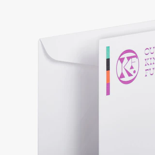 Two custom business envelopes printed with the Our Kinder Future name and logo in the top left corner.