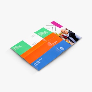 A nonprofit newsletter laying open with Our Kinder Future and a green, orange, blue and pink design.