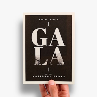 A hand holding a custom invite printed with a black and white design and Gala for the National Parks.