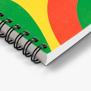 The bottom corner of a custom notebook printed with an orange, yellow and green cover and black spiral coils.