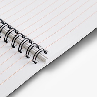 A notebook laying open to lined pages with black wire coils in sets of two binding it together.