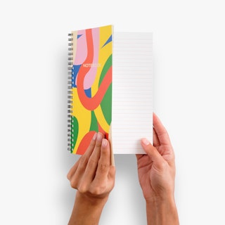 Two hands opening a custom notebook printed with an abstract cover design in pink, yellow, green, blue and orange.