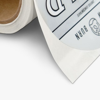 A roll of custom labels printed with an oval shape and a silver, black and white design.