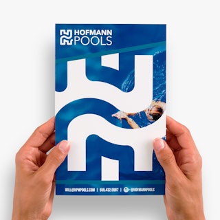Two hands holding a customized pamphlet printed with Hofmann Pools in white on a blue background.