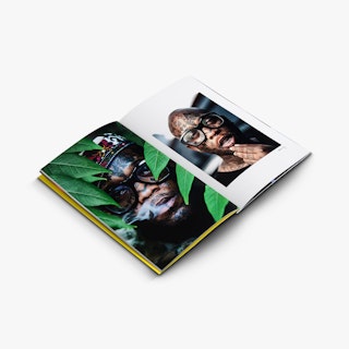 A photography booklet laying open to images of a man with tattoos on his face and thick, black glasses.