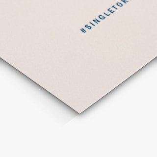 The bottom corner of a custom place card printed with a light pink background and #singletoklingel in black.