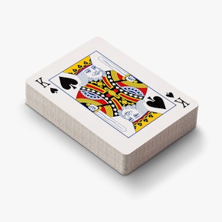 A deck of playing cards sitting at an angle with a king of spades on the top.