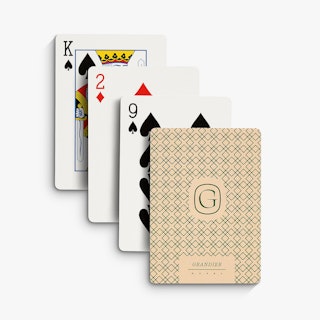 Four playing cards lined up and overlapping each other with one printed with a green and cream back.