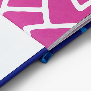 A hardcover portfolio laying open to a page printed with a pink and white design.