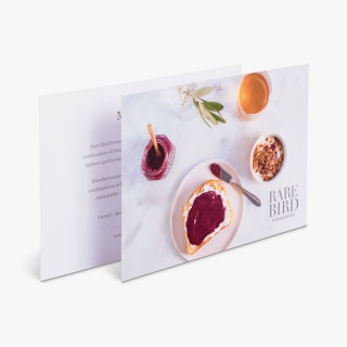 Two postcards standing overlapping each other and printed with jam, toast and Rare Bird on the front.