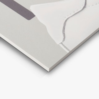 The corner of a PVC foam sign custom printed with a light and dark gray design and a white sneaker.