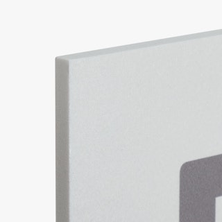 The top corner of a PVC foam sign printed with a light gray and dark gray design.