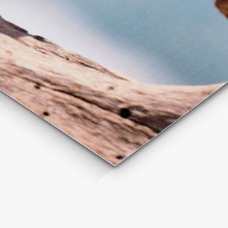 The corner of a custom rack card printed with a rock and sky design in brown and blue.