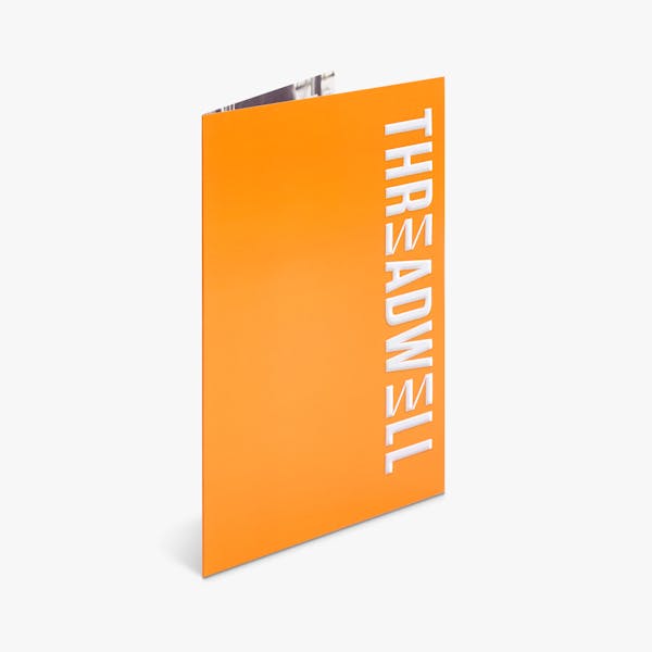 A spot UV pocket folder standing open with an orange design and Threadwell in white.