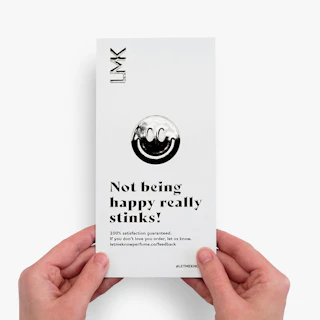 Two hands holding a rack card printed with a raised UV coating and fragrance brand messaging.