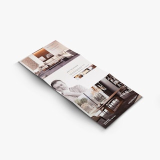 A real estate brochure laying open to images of a living room, dining room and the designer.