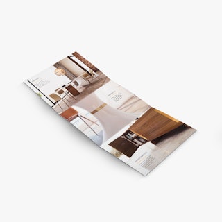 A tri fold brochure laying open to images of a dining room, a white table base and cabinet.