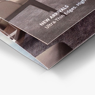 The bottom corner of a real estate brochure printed with a tri fold and New Arrivals in white.