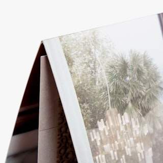 The top corner of a folded real estate brochure printed with an image of trees on the front.