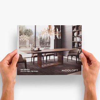 Two hands holding a real estate brochure printed with Modloft in white and an image of a dining room table.