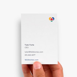 A hand holding a real estate business card printed with Tyler Forte CEO and contact information.