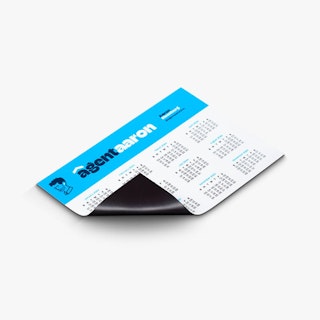 A custom calendar magnet printed with Agent Aaron in blue and white and one corner curling back.