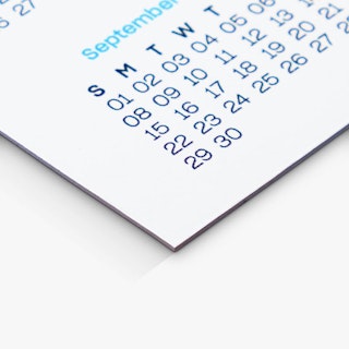 The bottom corner of a calendar magnet printed with the month and dates of September in blue.