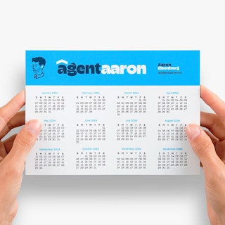 Two hands holding a magnetic calendar printed with Agent Aaron in blue and white at the top.