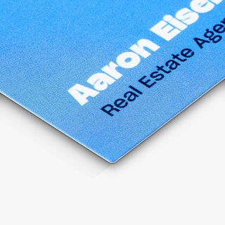 The bottom corner of a realtor postcard printed with an agent's name in white on a blue background.