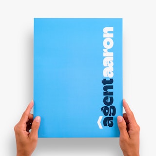Two hands holding a realtor pocket folder in solid blue with Agent Aaron in dark blue and white.