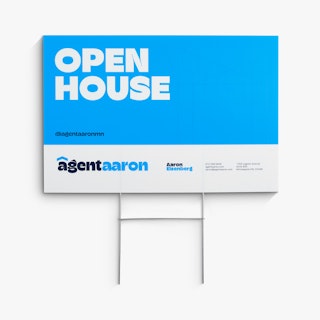 A real estate lawn sign printed with Open House and Agent Aaron in blue and white with an H-stake.