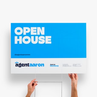 Two hands holding a real estate yard sign custom printed with an open house design in blue and white.