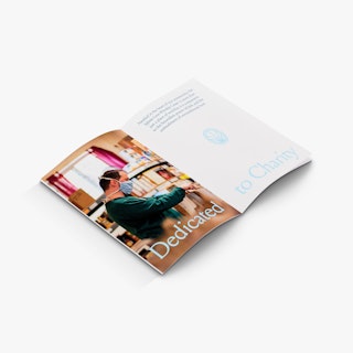 A church booklets laying open to a man wearing a mask and Dedicated to Charity in light blue.