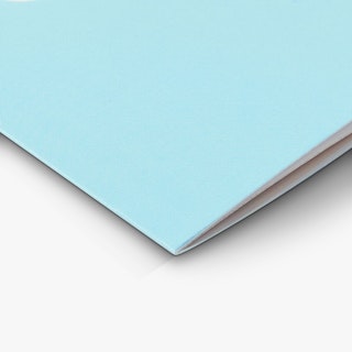 The bottom corner of a church booklet printed with a light blue background and saddle stitch binding.