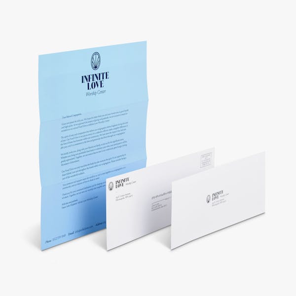 A religious letter mailer printed with Infinite Love behind a matching envelope and reply envelope.