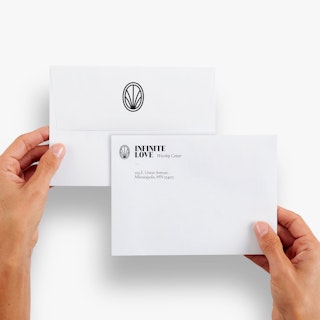 Two hands holding two custom offering envelopes printed with the Infinite Love name, address and logo.