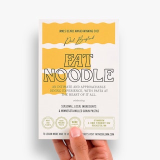 A hand holding a restaurant postcard printed with Fat Noodle and promotional information in yellow, green, black and white.