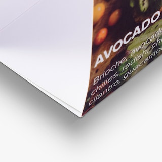 The bottom corner of a folded table tent printed with an image of and details for avocado toast.
