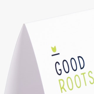 The top corner of a folded table tent printed with a white background and Good Roots in black and green.