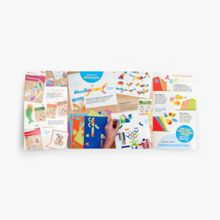 A right angle gate fold mailer laying flat with bright graphics of stationery and craft supplies.