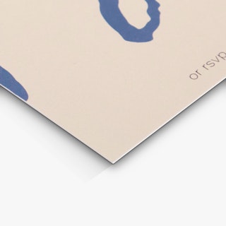 The bottom corner of an RSVP card printed with a cream background and blue and black text.