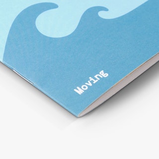 The corner of a saddle stitch booklet printed with a blue wave design and Moving in white in the bottom corner.