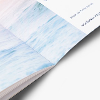 A saddle stitch booklet laying open to a pale blue ocean design.