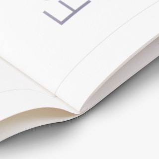 The bottom of the spine of a saddle stitch calendar laying open.