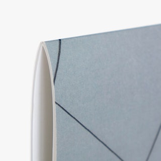 The corner of a custom calendar with a saddle stitch binding and a gray and black design on the cover.