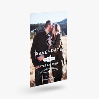 A save the date magnet printed with a man and woman smiling and Kyle & Justine in white.