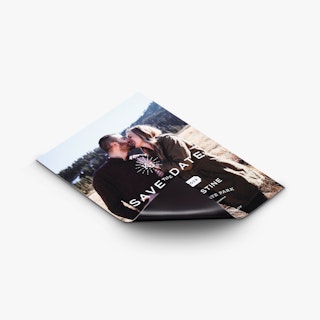 A custom save the date magnet printed with a smiling couple and the bottom corner curling back.