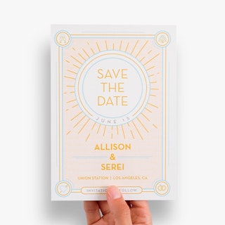 A hand holding a custom save the date postcard printed with Allison & Serei in yellow.